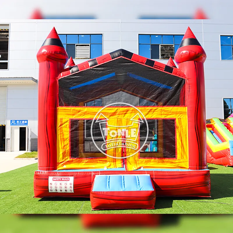 Red and yellow castle bounce house with black turret accents on green turf