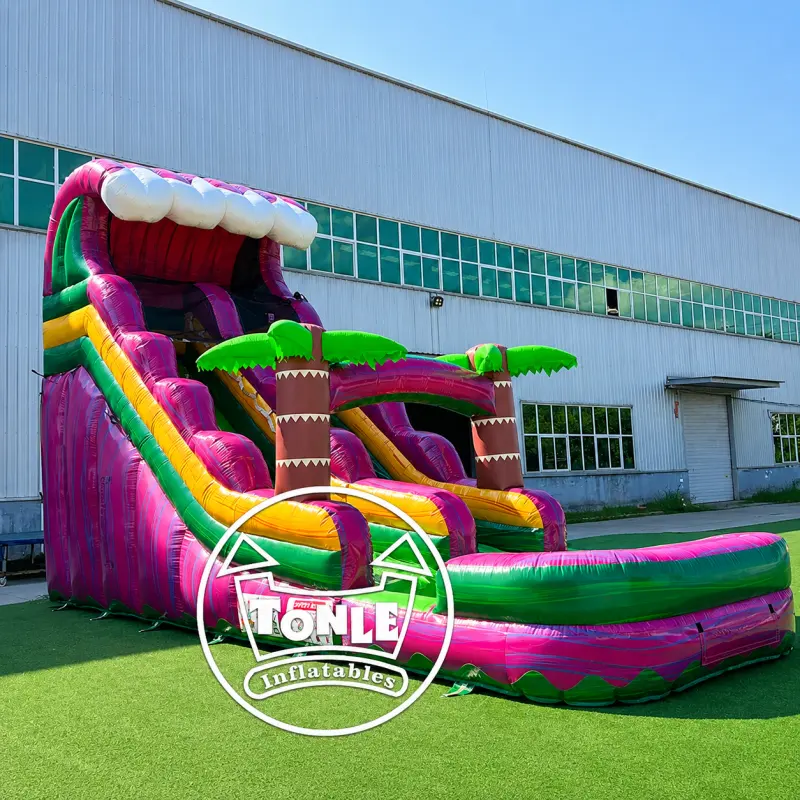 19ft pink and purple inflatable water slide with green palm trees and splash pool on grass