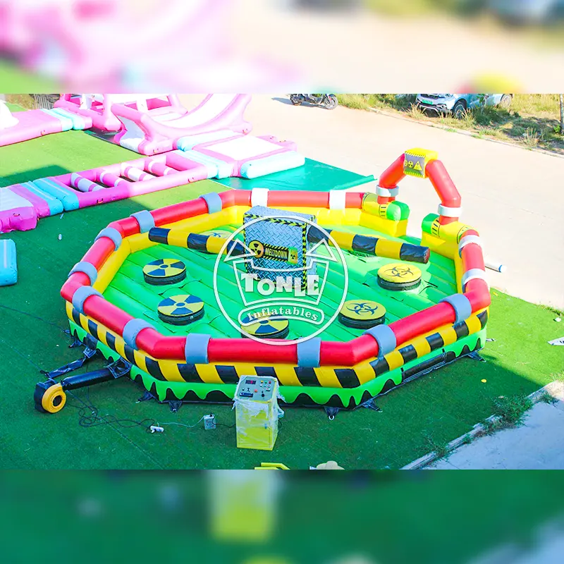 8m Toxic Meltdown mechanical inflatable sweeper game with green floor, yellow and black hazard stripes, and central rotating arm mechanism on grass.