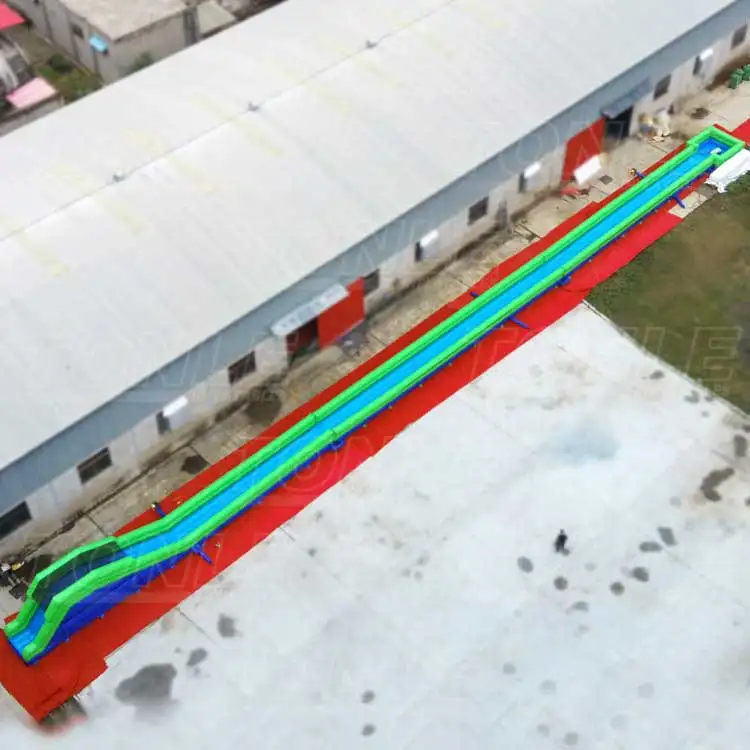 Aerial view of a 200ft long inflatable slip and slide with blue and green lanes and red borders on a concrete surface