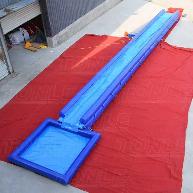 Blue 67ft single lane inflatable slip n slide with square splash pool on red ground tarp