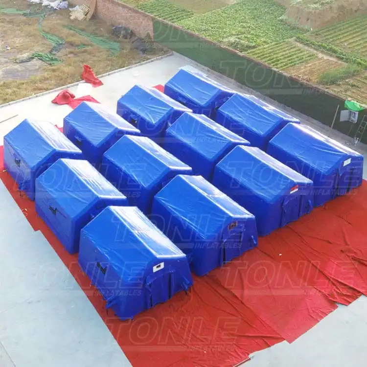 Row of blue 4.3x3.4m inflatable medical tents on red ground sheet