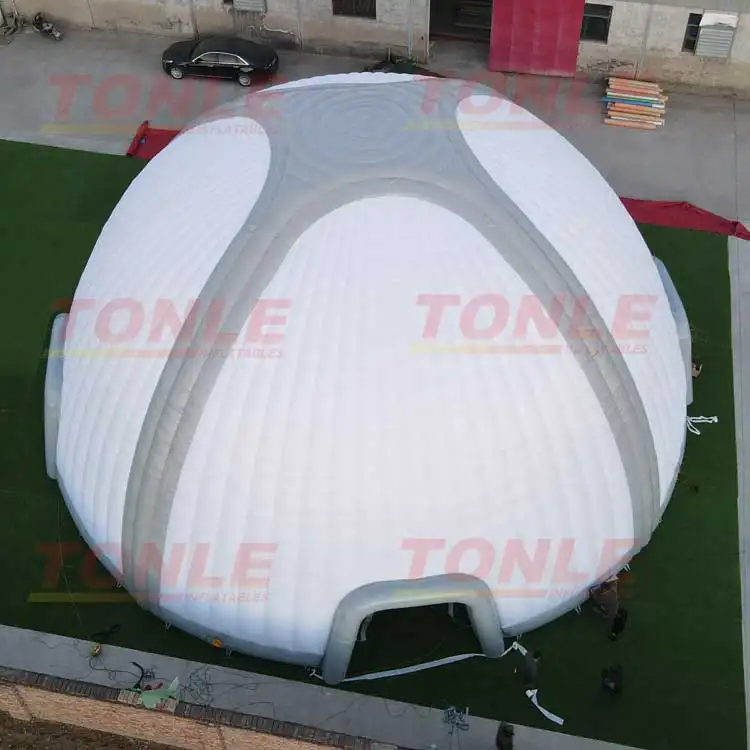 Aerial view of a large white and grey inflatable dome tent measuring 20x20m on a green surface