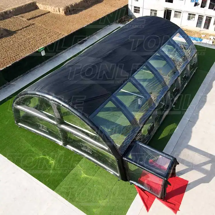 Black inflatable water pool tent with clear windows on green turf
