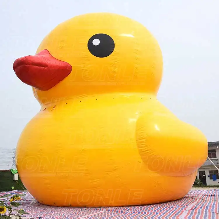 Side view of a 14.2m giant yellow inflatable duck with a red beak on a striped tarp
