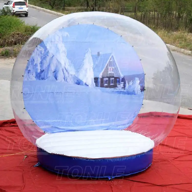 3m diameter inflatable snow globe with transparent dome and blue base featuring a winter house backdrop