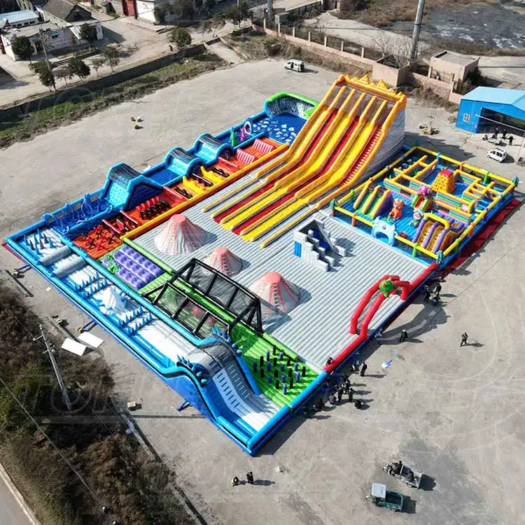 Aerial view of 50x40m Monster Slide Theme Park inflatable with yellow slides and blue obstacle course