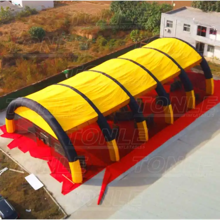 Aerial view of a large yellow and black inflatable bunker field with arched supports on a red ground tarp
