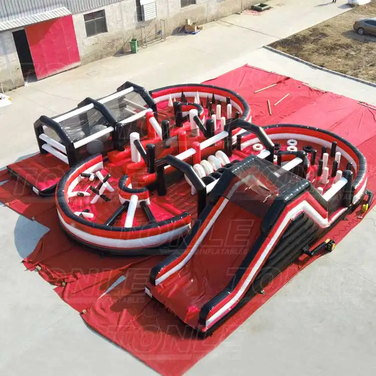 Aerial view of a large red, black, and white 14x16m inflatable obstacle course with dual circular zones and a slide