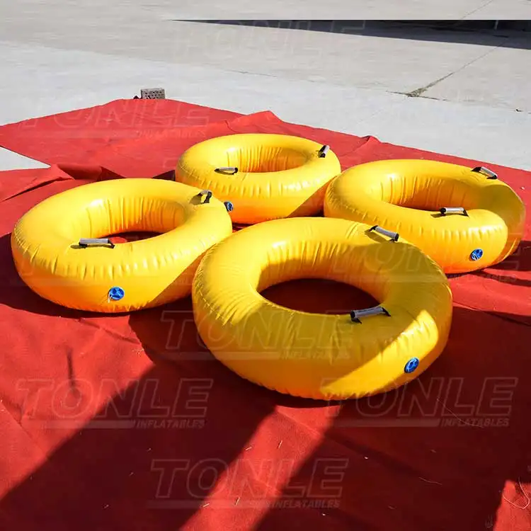 Four yellow 1m inflatable swimming rings with black handles on red tarp