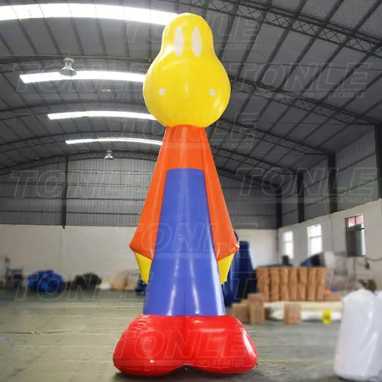 6m tall inflatable man with yellow head, orange cape, blue body, and red feet standing in a warehouse
