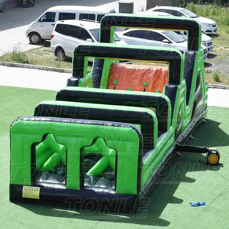 Green and black 11.7m inflatable obstacle course with orange climbing wall section