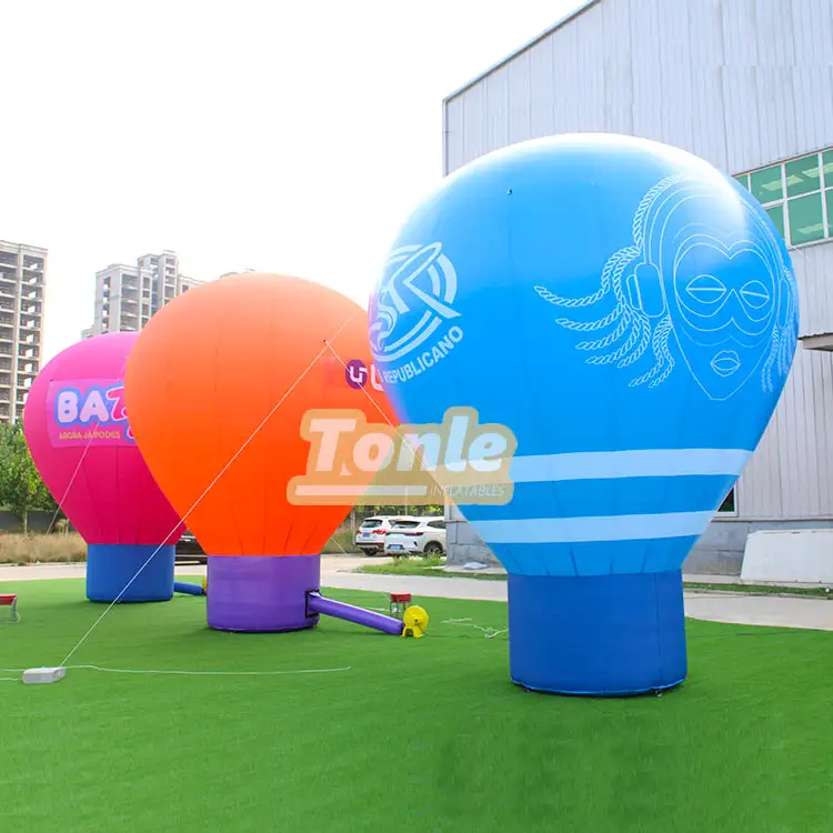 Three 5m tall inflatable advertising balloons in blue, orange, and pink with custom graphics on green turf