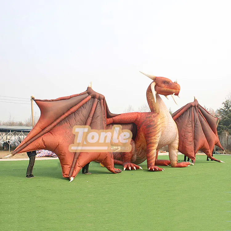 Giant red inflatable dragon replica with spread wings on green turf