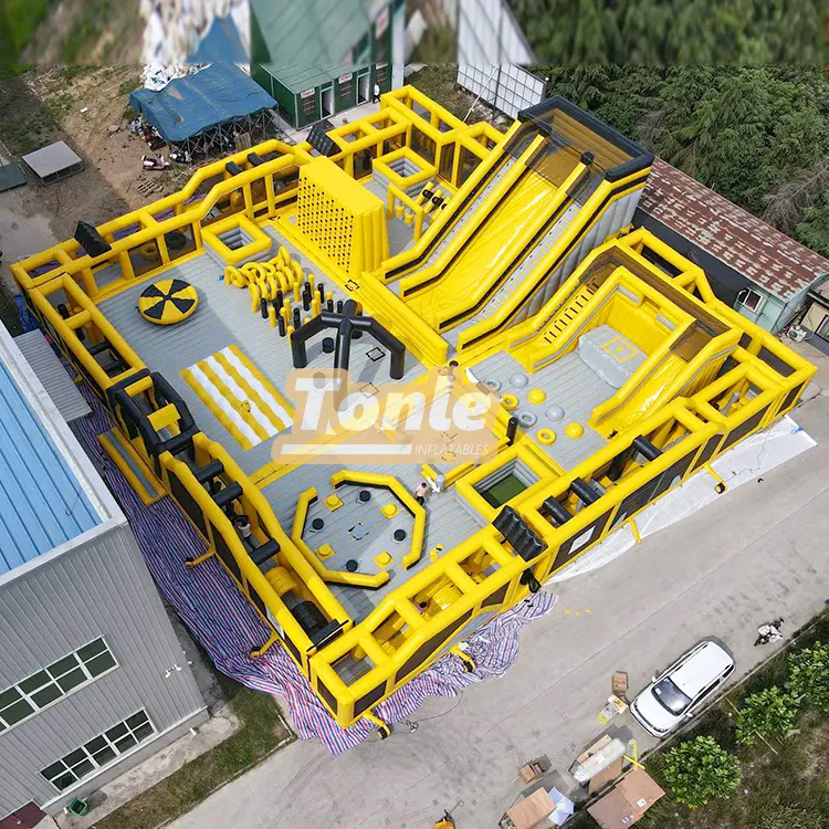 Aerial view of 30x30m yellow and black inflatable fun city with slides and obstacles