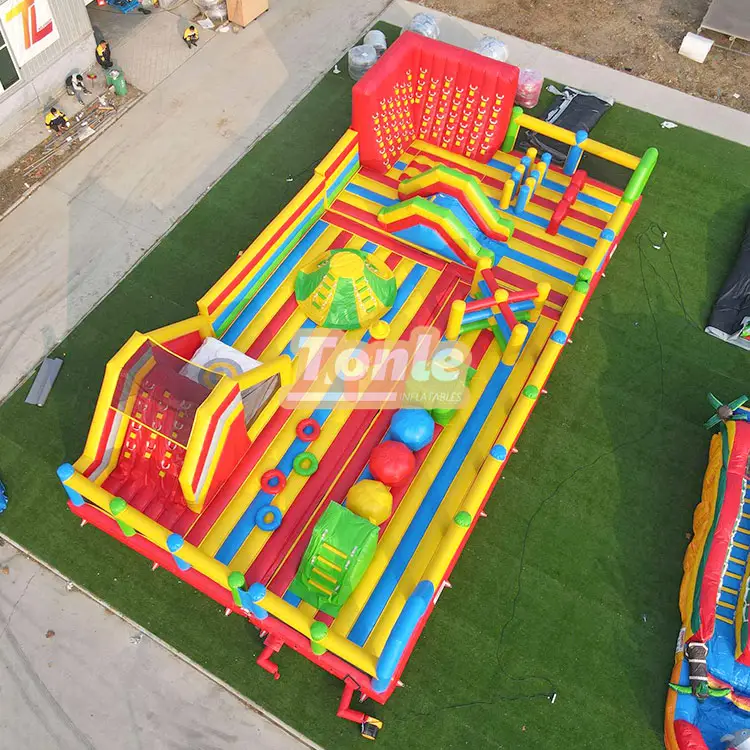 Aerial view of 18x9m red yellow and blue inflatable circus obstacle park with slide and climbing wall