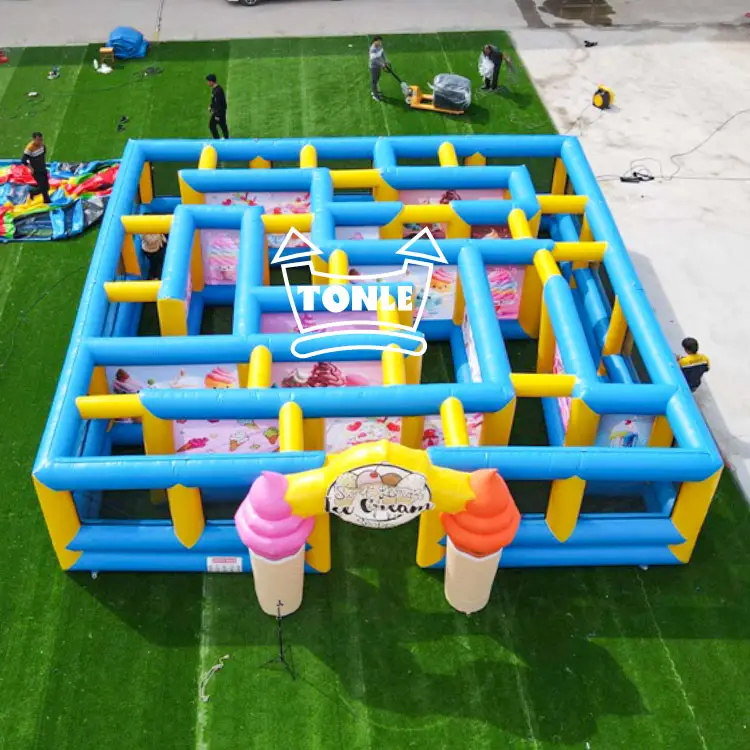 Aerial view of a 7x7m blue and yellow inflatable maze with ice cream cone entrance decorations on green turf