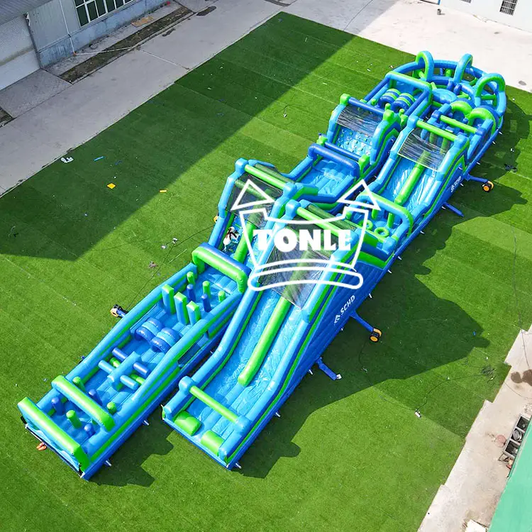 Aerial view of a large blue and green U-shaped inflatable obstacle course on artificial turf