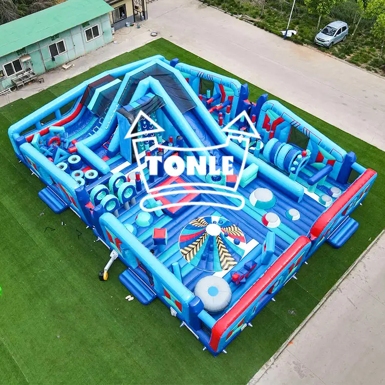 Aerial view of blue and red 17x12m inflatable fun city with science theme graphics on green turf