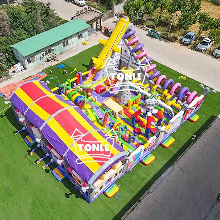Aerial view of 20x15m inflatable fun park with purple and yellow striped roof and city theme graphics