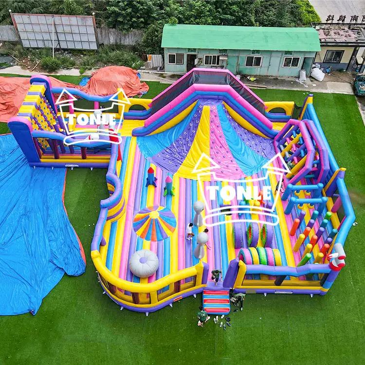 Aerial view of large colorful inflatable fun park with slide and obstacles on green turf