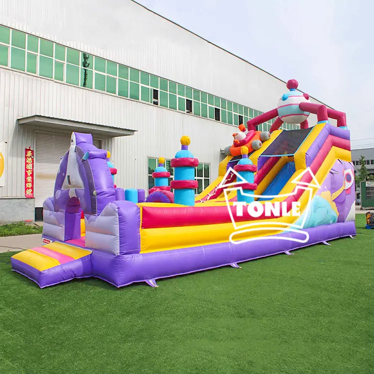 Purple and yellow 8m inflatable dry slide with unicorn entrance and castle turrets on green turf