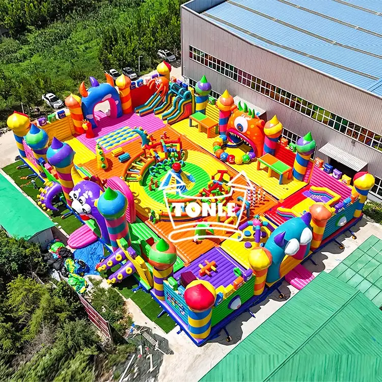 Aerial view of a large colorful inflatable playground complex featuring multiple slides and obstacle courses at a manufacturing facility