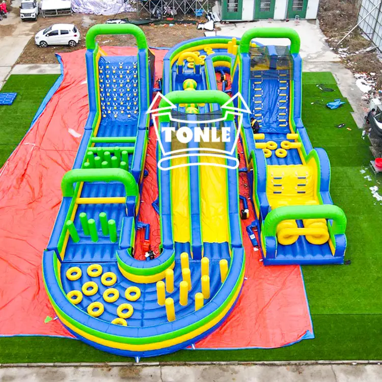 Aerial view of a 27.5m starry sky blue inflatable obstacle course featuring three parallel lanes with green arches, yellow slides, and blue climbing walls on a red ground tarp.