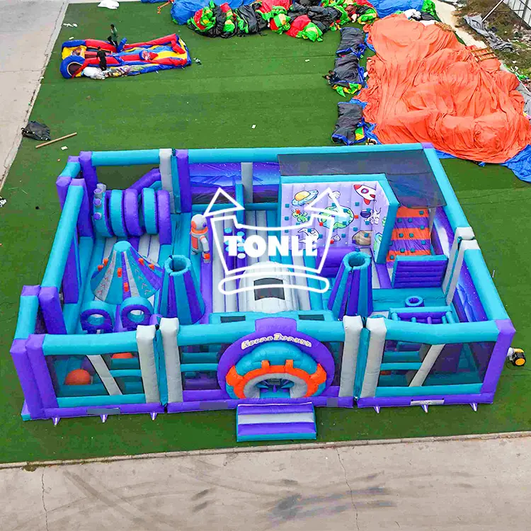 Aerial view of purple and teal inflatable space theme park with rocket graphics on green turf