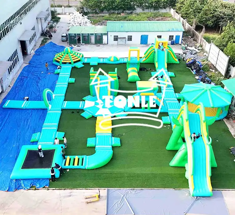 Aerial view of 37x37m cyan and yellow floating water park with slides and trampolines
