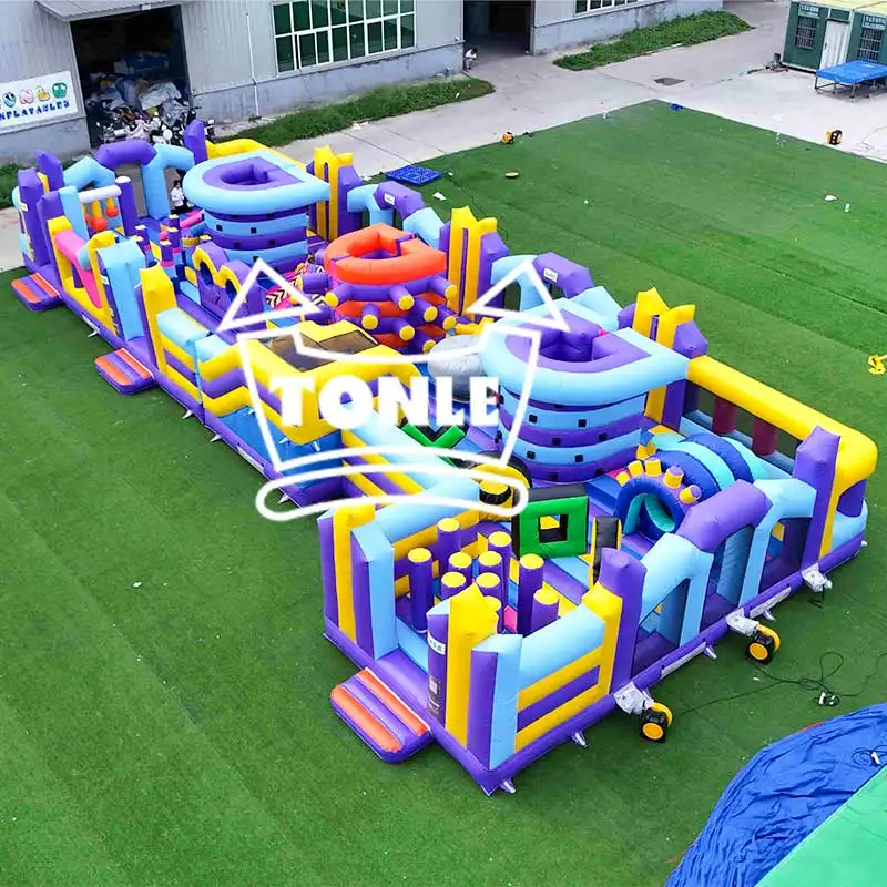 Aerial view of a 22m purple and yellow inflatable fun city obstacle course on green turf