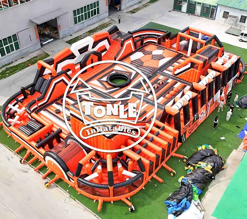 Aerial view of 30x20m orange and black inflatable fun park with multiple obstacle zones