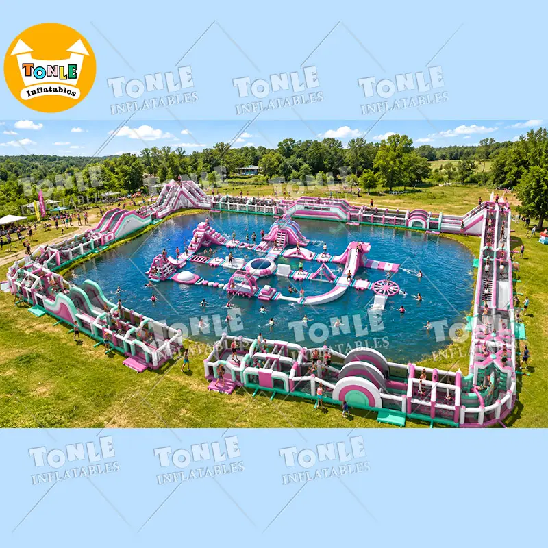 Aerial view of the 49x80M Rose Red Water Park featuring pink and white inflatable slides and obstacles on a lake